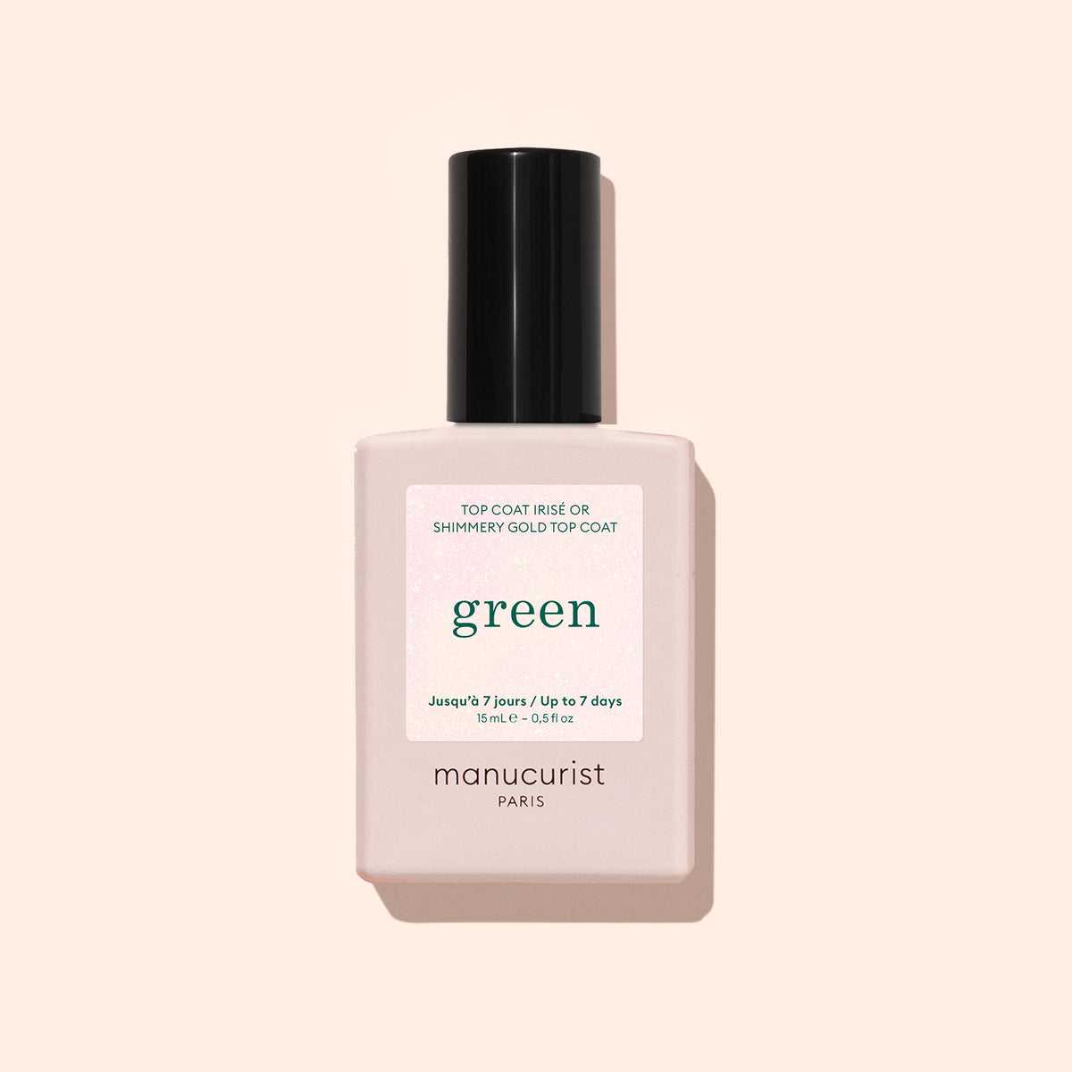 Un flacon de Manucurist Glitter Top Coat, dans un flacon carré rose pâle avec bouchon noir et étiquette blanche sur fond beige clair, offrant une formule express qui sèche à l&