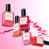 Five bottles from Manucurist’s Curated Color Collections are arranged on a pink gradient background, featuring swirling polish strokes that showcase the brand’s trend-forward shades perfect for stylish manicures.