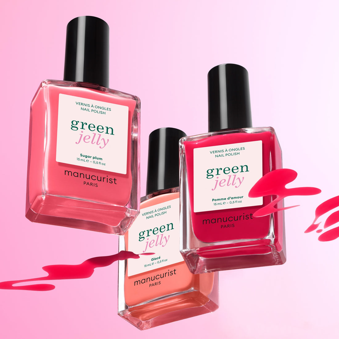 Three bottles of Manucurist Curated Color Collections nail polish in pink shades float on a pink background with matching splashes—ideal for on-trend manicures inspired by curated palettes.