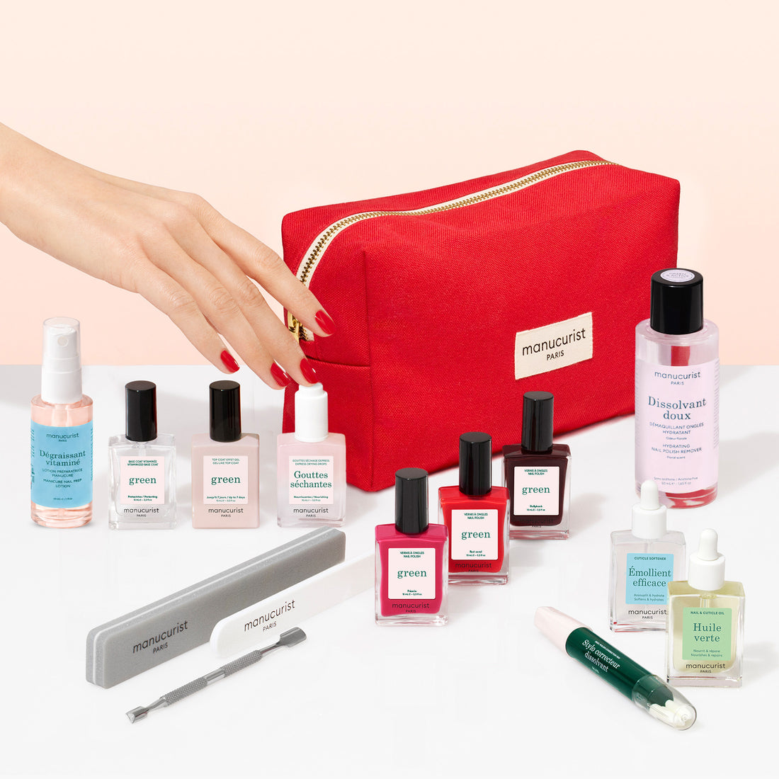 A hand reaches toward a Green™ Ultimate Kit and a red zippered pouch on a white surface.