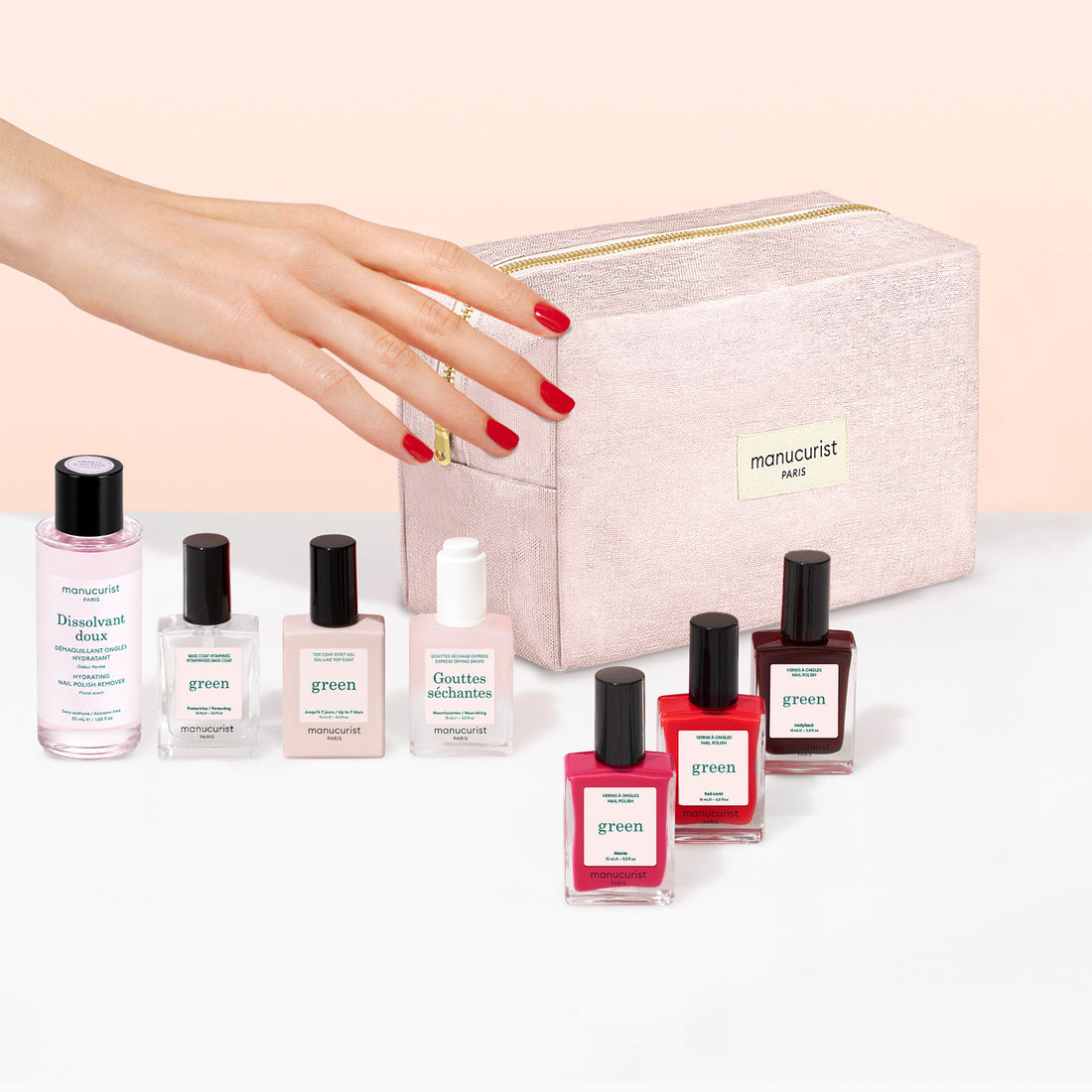 A hand with red nail polish reaches for a pink makeup bag, surrounded by bottles of nail polish remover and an assortment of Manucurist Starter Kit plant-based nail polishes, including options for a green manicure and gel effect manicure.