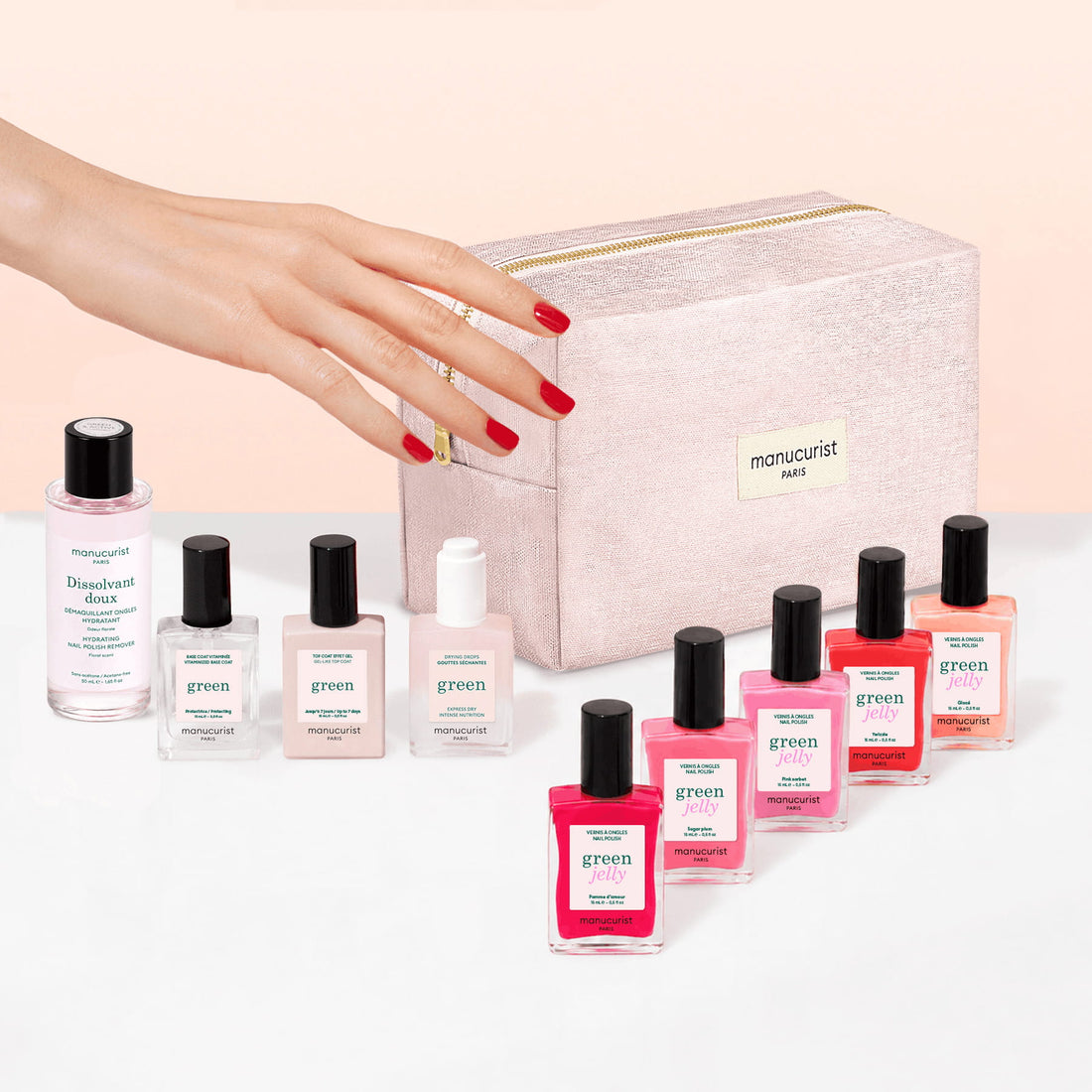 A hand with red nails reaches toward a pink zipper pouch, surrounded by bottles from the Manucurist Super Starter Kit - Jelly Nail Polish—featuring a variety of plant-based gel effect shades—and a gentle nail polish remover.