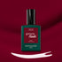 Un flacon de vernis LED Amour de Manucurist repose sur une surface rouge profond. En dessous, un trait de vernis blanc met en valeur la teinte bordeaux lumineuse de ce vernis gel emblématique.
