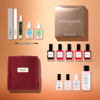 A flat lay of the Manucurist Green™ Super Starter Kit Gift Set, featuring eight naturally derived nail polishes, remover, treatment oils, a file, cuticle pusher, and a burgundy kit bag—everything you need for the ultimate nail prep—beautifully arranged on a peach background.