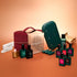 The Manucurist Green Flash™ Super Starter Kit Gift Set—including several bottles of nail polish, a burgundy carrying case, a green nail lamp, and nail files—is displayed alongside miniature gold dollhouse furniture on an orange and beige gradient background, providing everything you need for salon-style manicures and long-lasting nails at home.