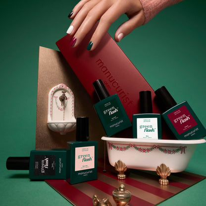 Une main aux ongles multicolores survole un coffret cadeau portant le nom de Manucurist. Six flacons de vernis à ongles des Collections de couleurs sélectionnées, inspirées des palettes de couleurs Green Flash, sont disposés dans et autour d’une petite baignoire décorative, tandis qu’un minuscule lavabo orné se trouve à l’arrière-plan. Les tons verts et rouges mettent en valeur les dernières tendances manucure.