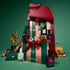 Manucurist’s Advent Calendar Time to Flash! features numbered doors, manicure essentials, and a festive red bow. In front sit bottles of nail polish—including Green Flash gel polish—and a Keratine booster. Decorative accents and a small cat figurine add charm against the green backdrop.