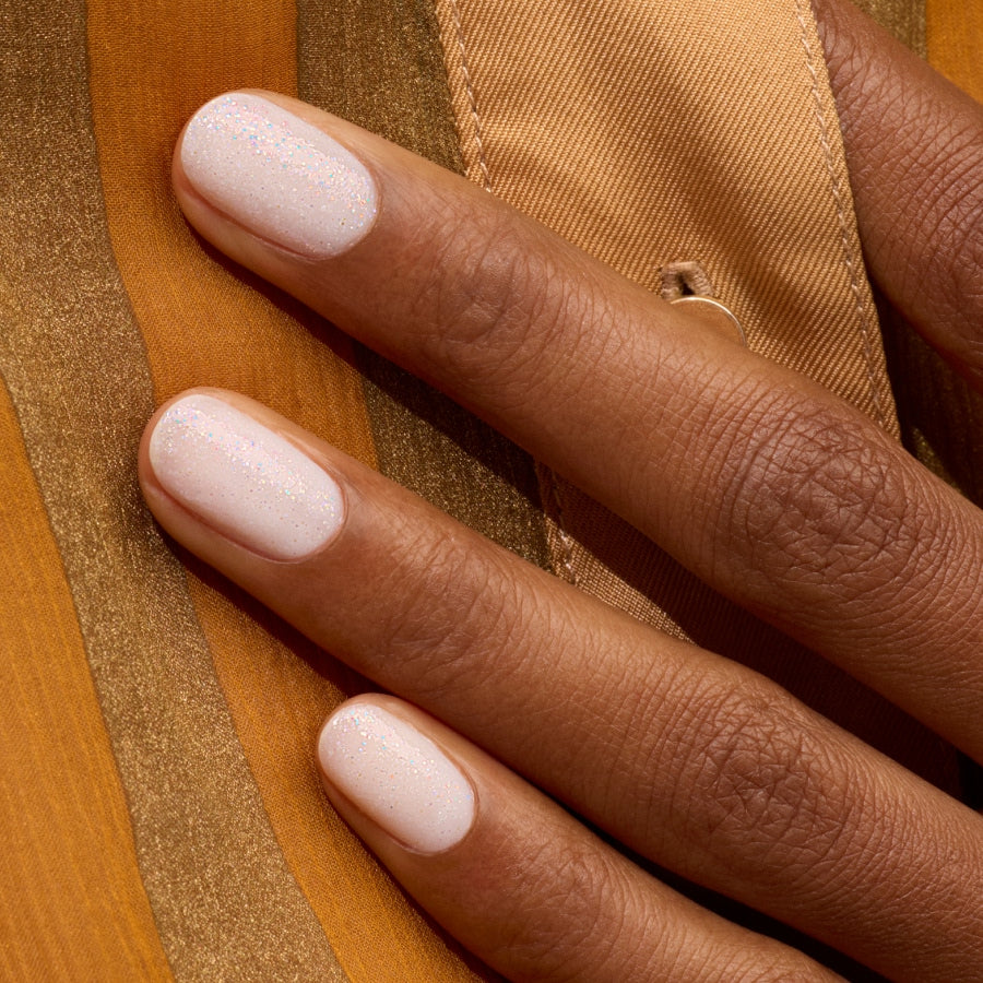 A close-up of a hand with medium brown skin shows neatly manicured nails painted in Manucurist&