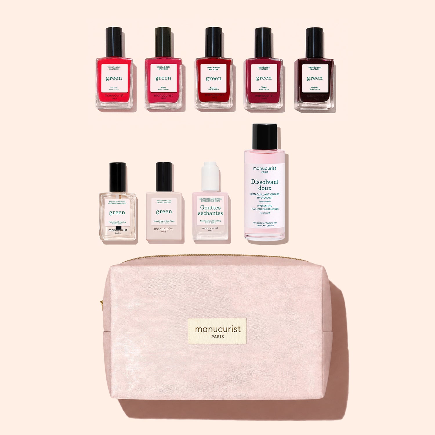 Nine manicure products from Manucurist’s Super Starter Kit—including seven bottles of plant-based nail polish, one remover, and one drops—are arranged above a pink zippered makeup bag labeled “manucurist PARIS” on a light pink background.