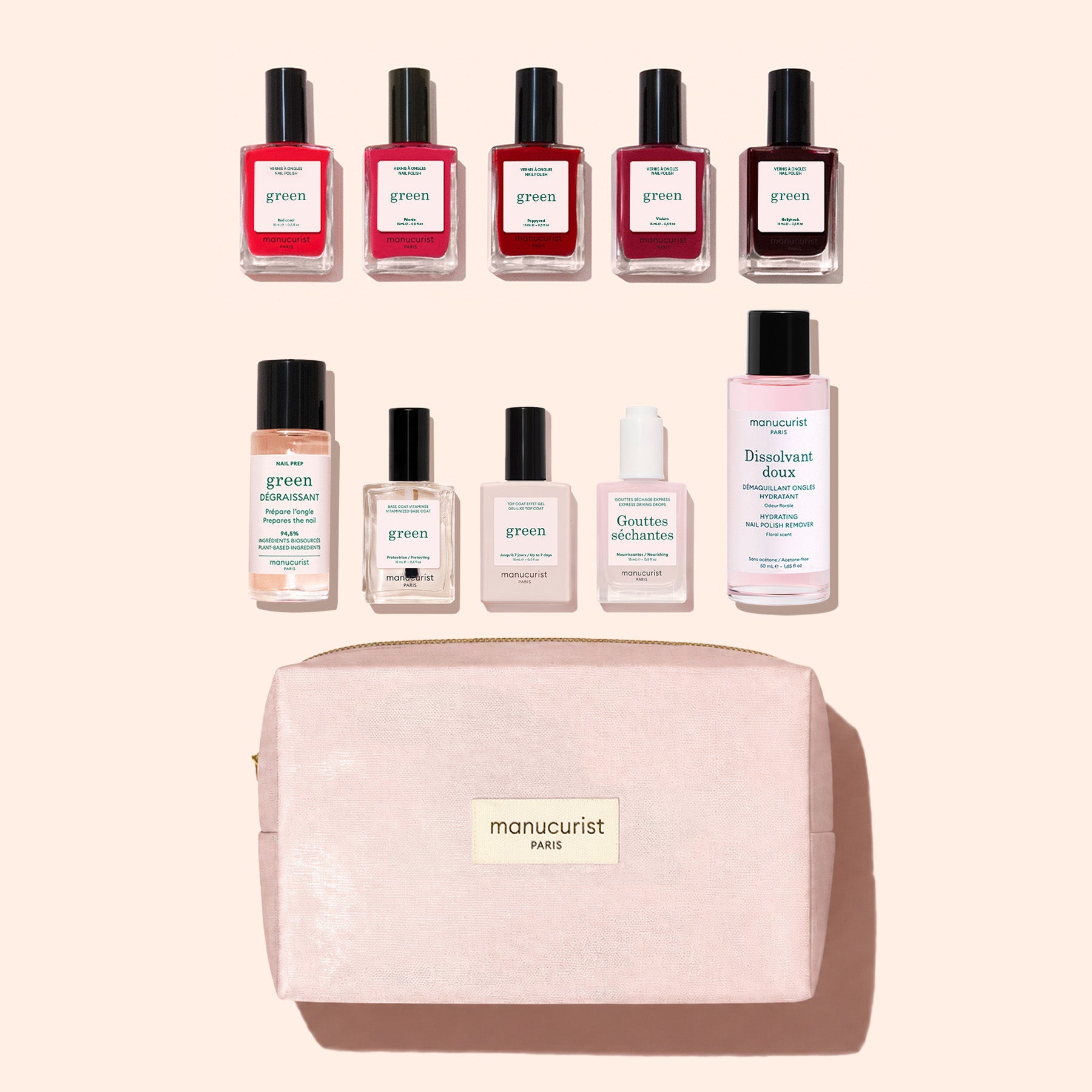 Nine bottles of Manucurist plant-based nail polish and a pink bottle of nail polish remover are arranged above a light pink zippered pouch labeled “manucurist PARIS” from the Super Starter Kit, all set against a light background.