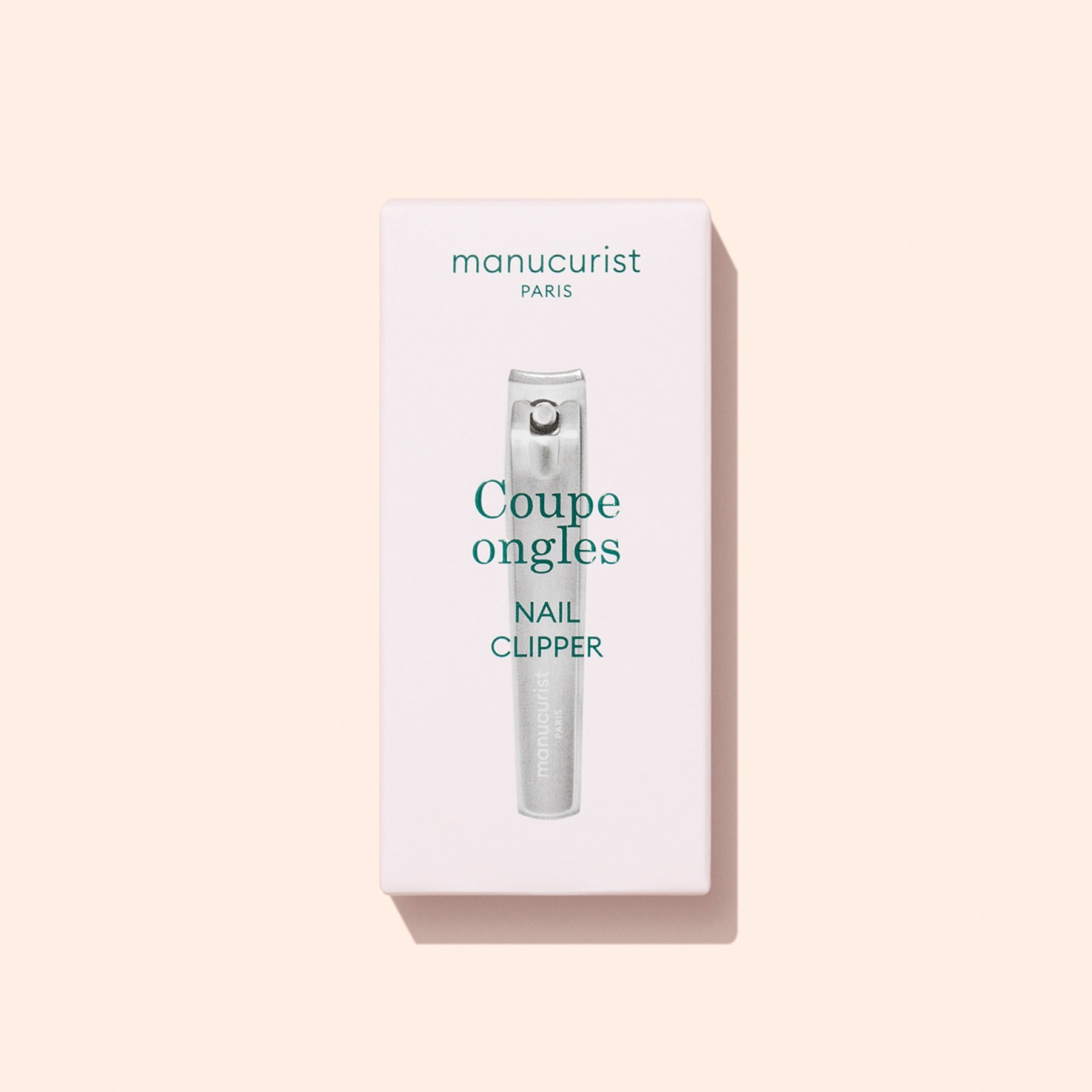 A box of Manucurist Nail Clipper, a precision nail cutter and must-have manicure tool, featuring the text “Coupe ongles Nail Clipper” on a light pink background.