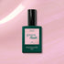 A bottle of Manucurist Halo gel polish stands upright on a shimmery pink background. The dark green bottle with a pale pink label features the product name "Halo" and the Manucurist brand for this innovative LED nail polish.