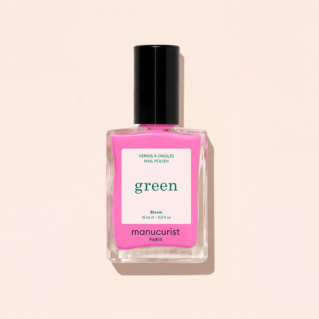 A 15 mL Manucurist Bloom neon pink nail polish with blue undertones and a black cap. The label says “green,” “Bloom,” and “15 mL – 0.5 fl oz.” The bottle casts a shadow on a light background.