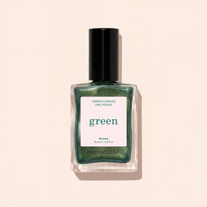 A glass bottle of pearly green nail polish with a black cap is shown against a light beige background. The label reads Groove by Manucurist.
