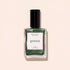 A glass bottle of pearly green nail polish with a black cap is shown against a light beige background. The label reads Groove by Manucurist.