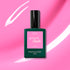 A bottle of Manucurist Bloom gel polish rests on a pink background with white streaks. The dark green bottle features a pink label marked “green flash” and “Bloom,” creating a magnetically intense look.