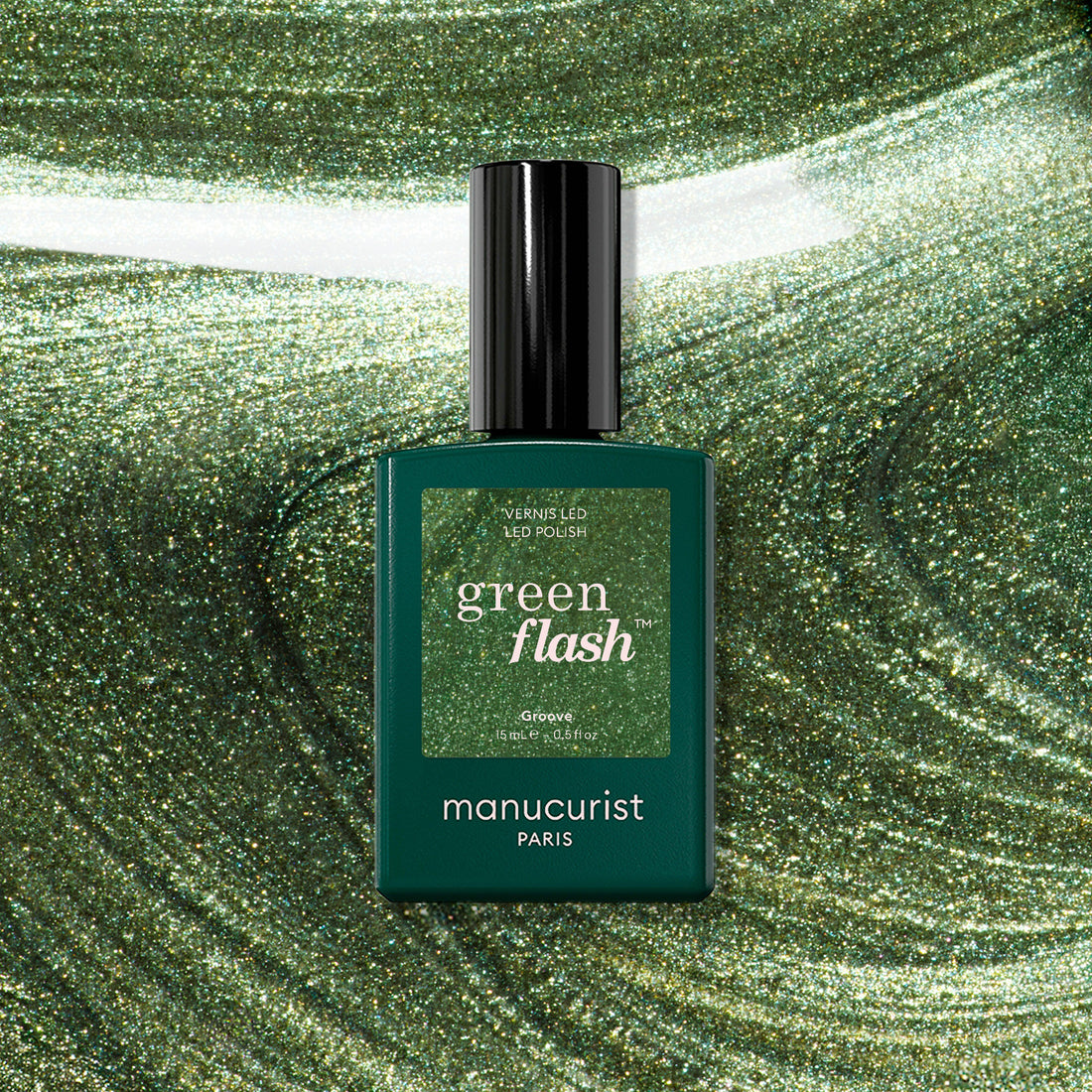 A bottle of Manucurist Groove Green Flash gel polish rests on a swirling, shimmering green background that matches the bold metallic green shade of this striking Manucurist color.