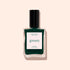 Un flacon de vernis Emerald de Manucurist, inspiré des pierres précieuses et doté d’un bouchon noir, est présenté sur un fond beige clair.