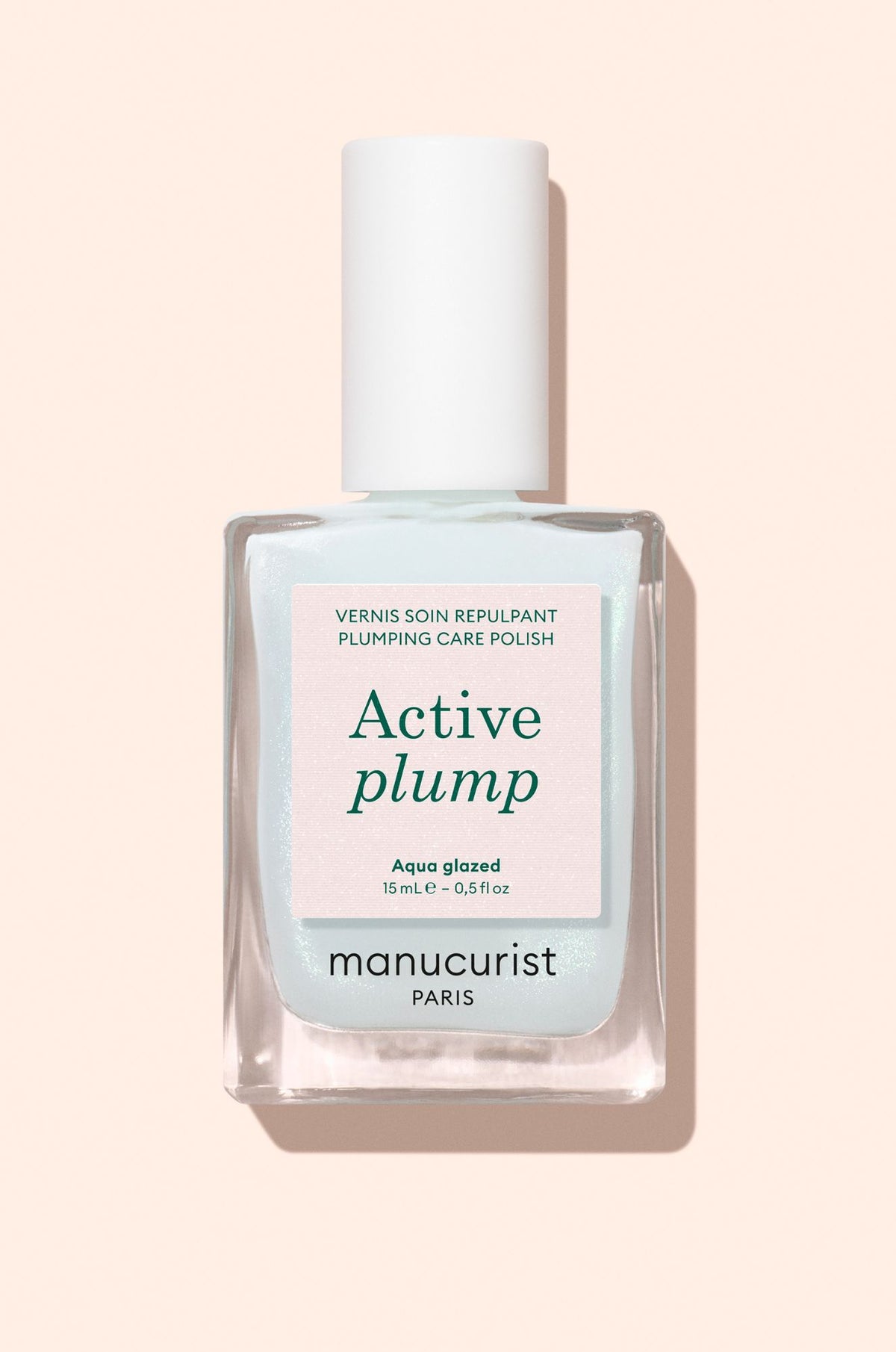 A square glass bottle of Manucurist Active Plump Plumping Care Polish in Aqua glazed shade with a white cap, positioned upright against a pale pink background.