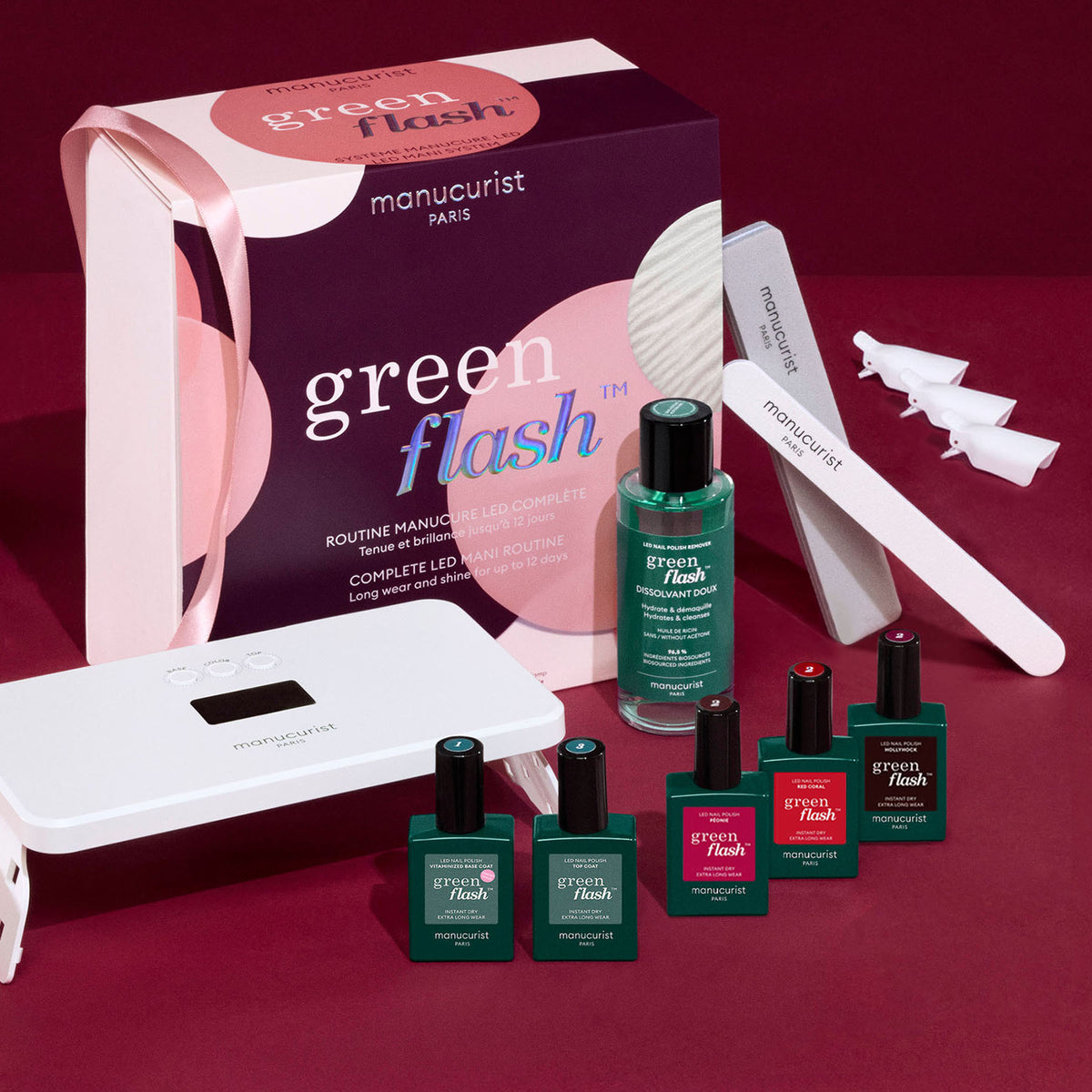 The Manucurist Starter Kit Gift Set (TEST COFFRET) is displayed on a red surface, featuring semi-permanent Green Flash nail polishes, a nail file, LED lamp, acetone-free remover, clips, and a green and white branded box.