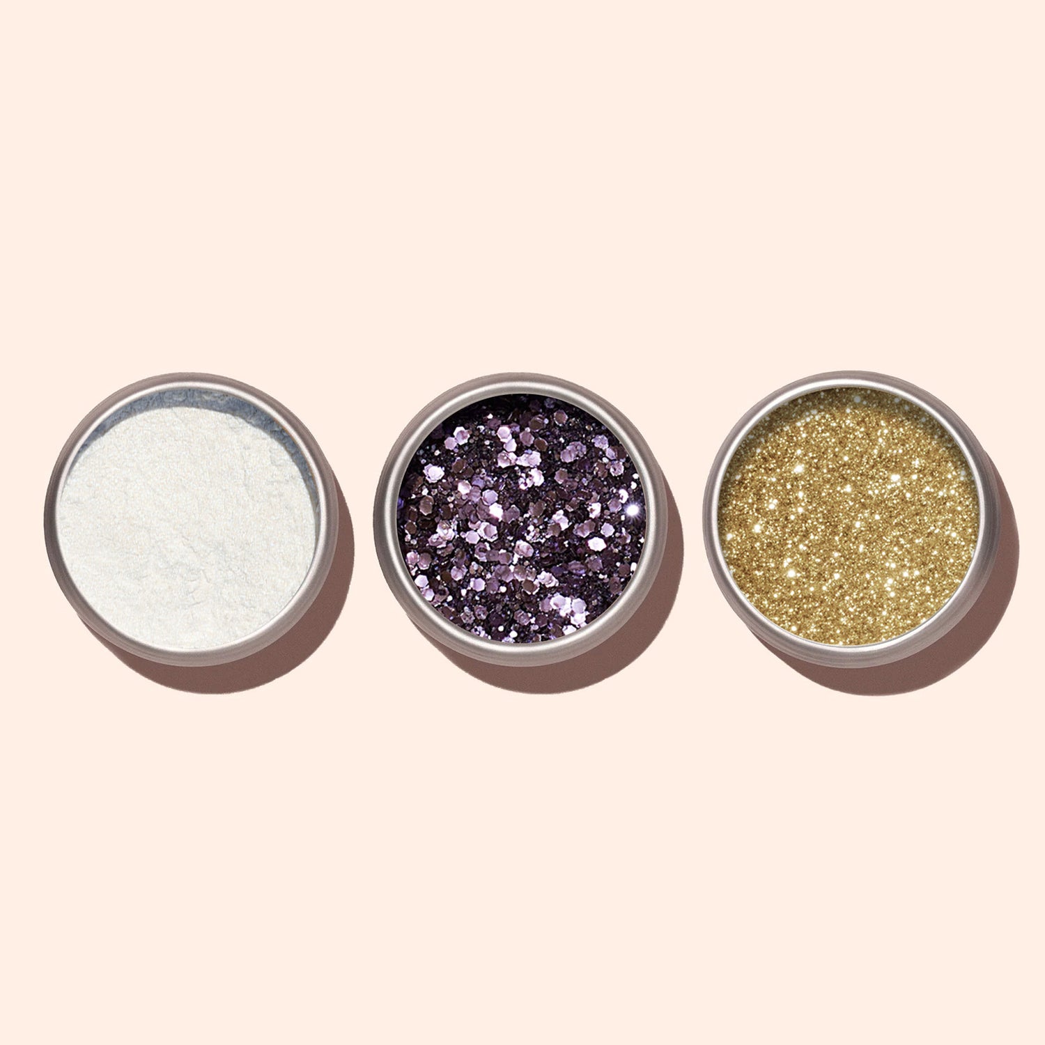 Three small round containers hold white powdery glitter, chunky purple glitter, and fine gold glitter—ideal for manicures or pairing with Manucurist&
