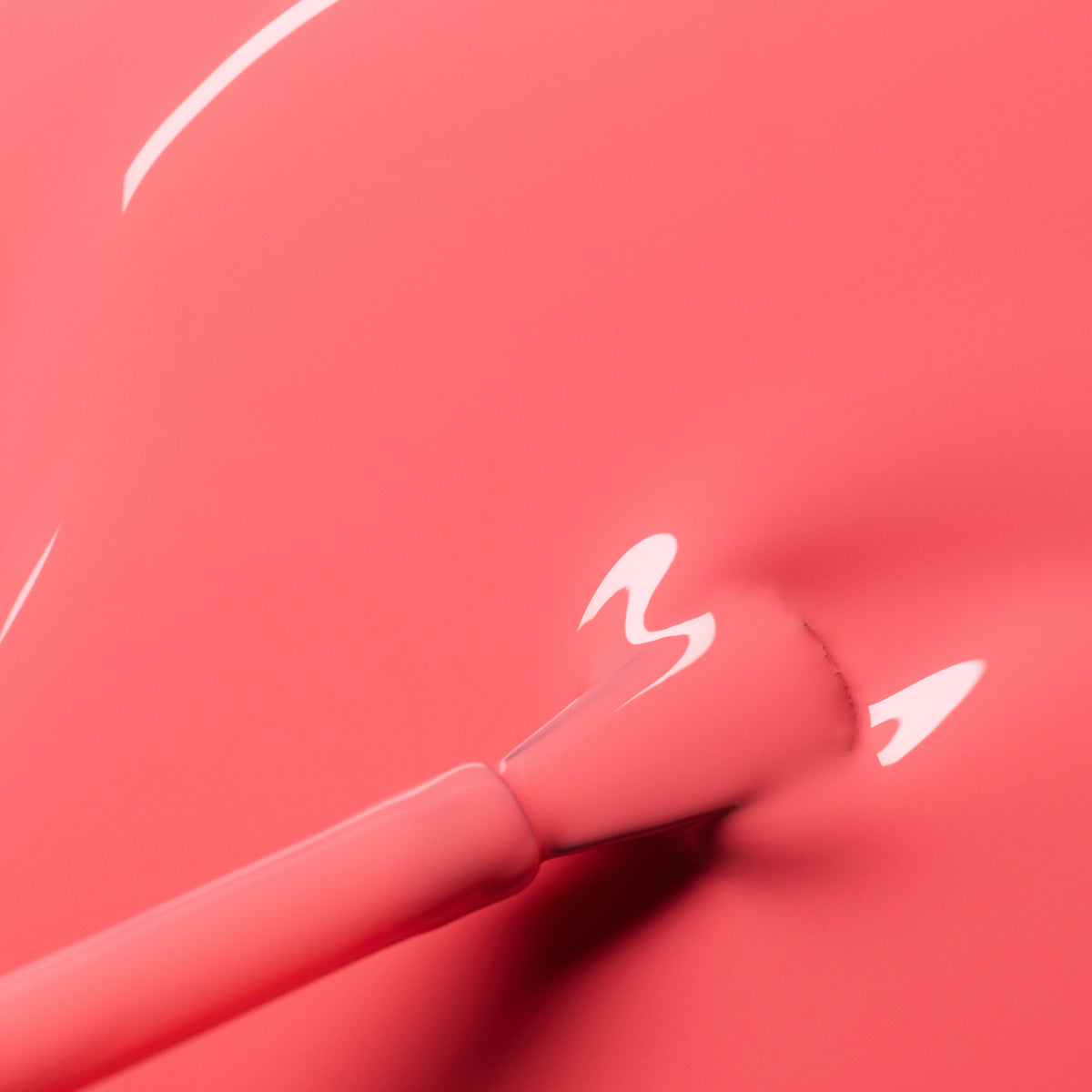 Gros plan sur un pinceau appliquant le vernis semi-permanent Capucine de Manucurist, une teinte rose corail brillante avec des reflets de lumière scintillants sur sa surface lisse et humide.