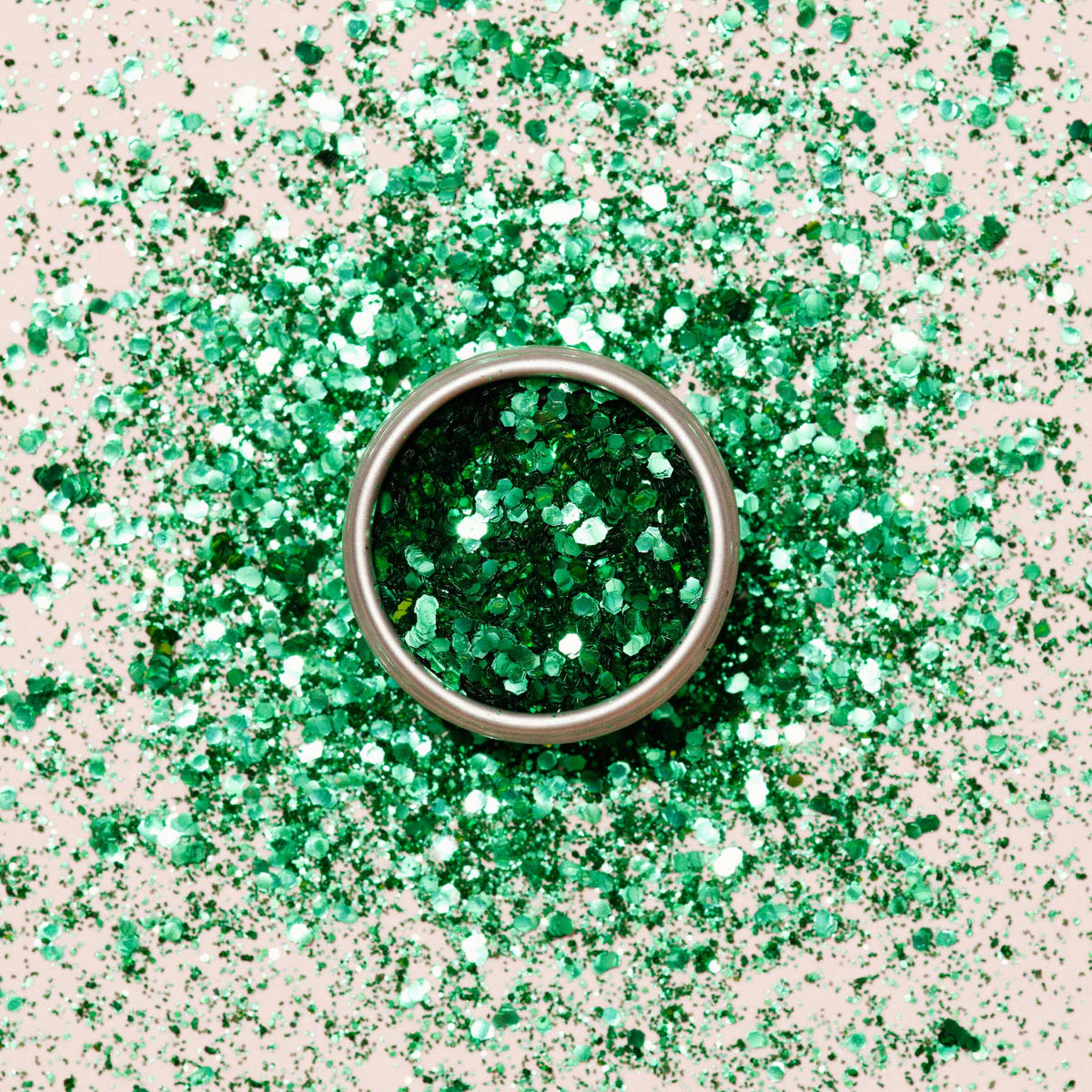 Un pot rond en métal de Paillettes biodégradables Cactus Manucurist est posé sur une surface, entouré de paillettes vertes éparpillées — parfait pour des créations Nail Art pleines d&