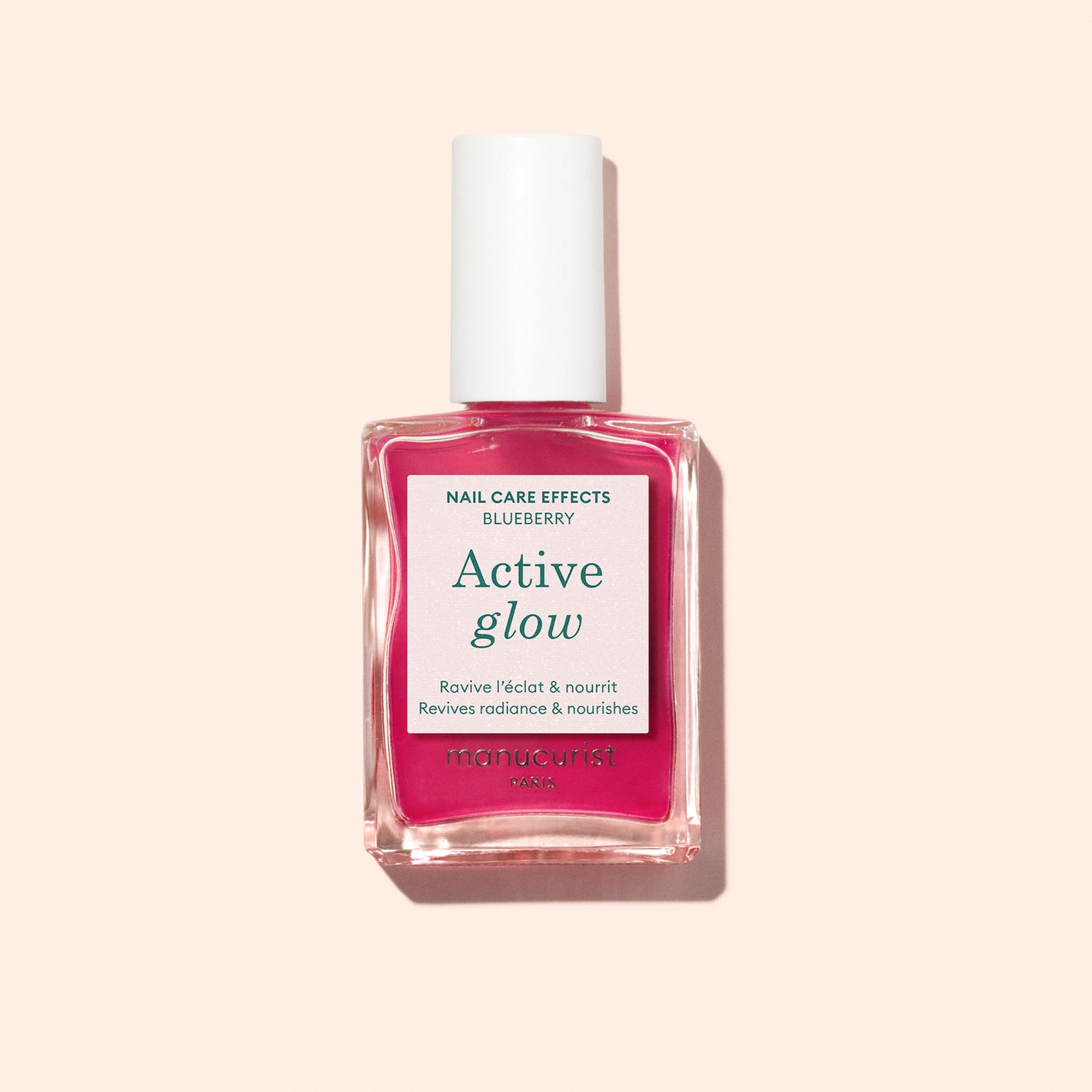 Manucurist Active Glow Blueberry is a rectangular nail care polish in pink that revives radiance and nourishes nails, serving as a nail enhancer for radiant shine, shown against a pale peach background.