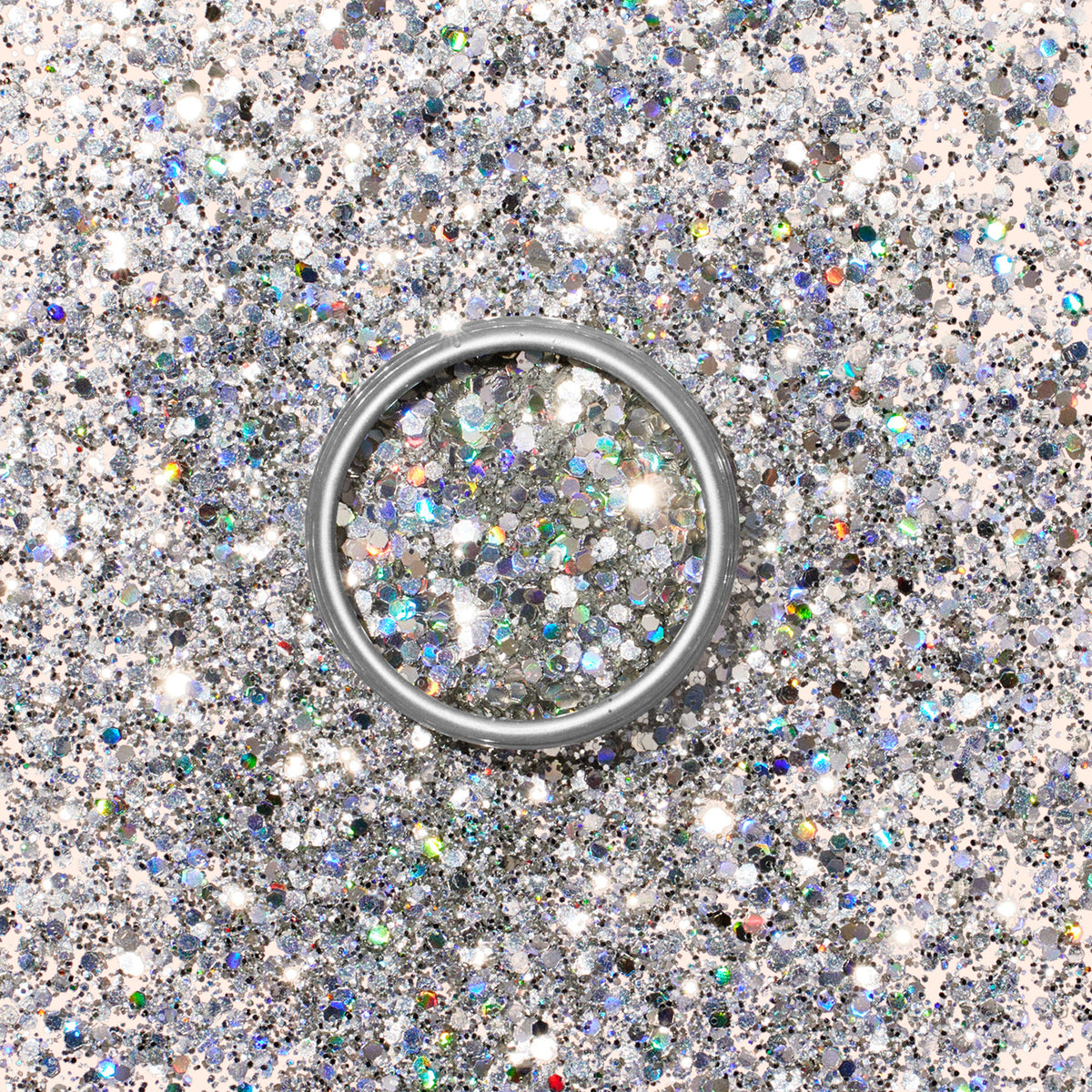 Une bague en argent repose sur une surface saupoudrée de Paillettes Biodégradables Holo Manucurist, reflétant la lumière pour un effet scintillant et écoresponsable, parfait pour inspirer vos manucures Nail Art.
