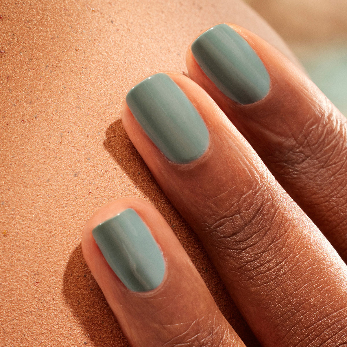 A close-up of a dark-skinned hand with neatly manicured nails painted in Manucurist&