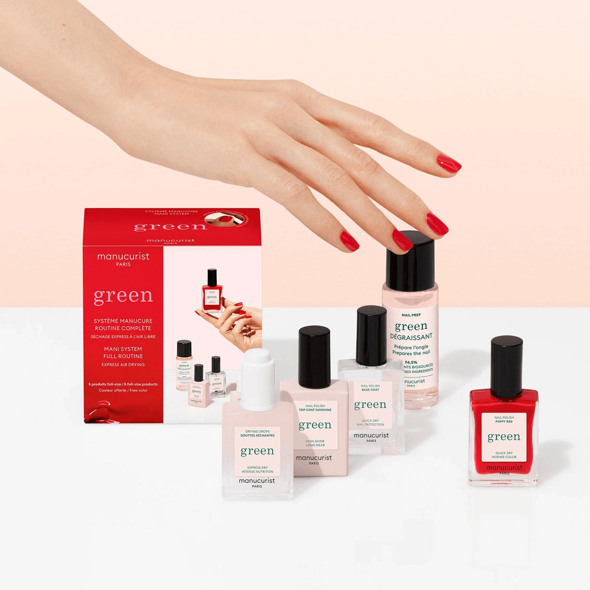 Une main aux ongles vernis de rouge survole des produits de manucure Manucurist, dont trois vernis à ongles biosourcés, un vernis rouge effet gel et le coffret rose et rouge Discovery Kit, disposés sur une surface blanche sur fond rose pâle.