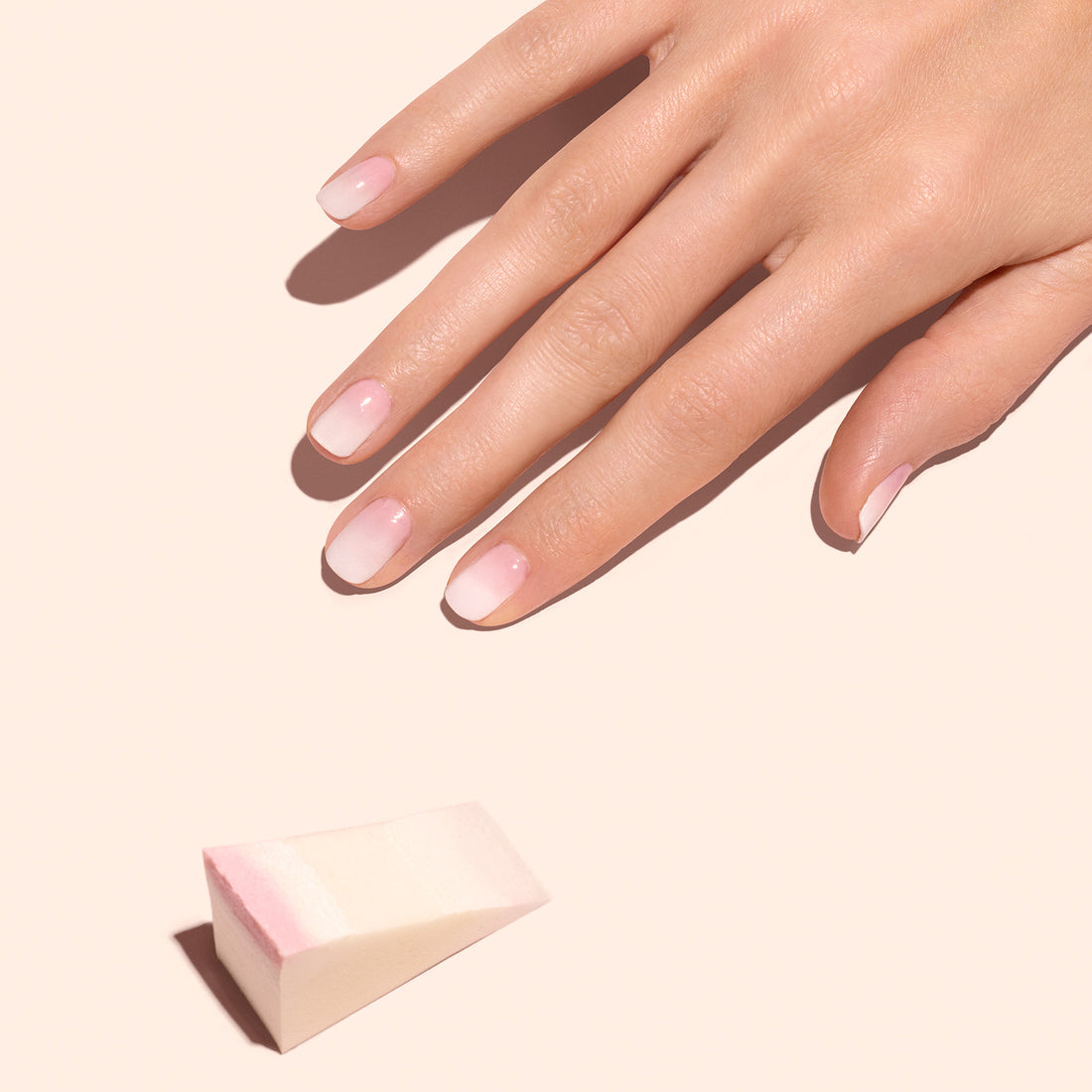 A hand with neatly manicured, natural nails rests on a light surface. Nearby, Manucurist Nail Art Sponges - x4 suggest the perfect tool for creating soft Baby Boomer nails.
