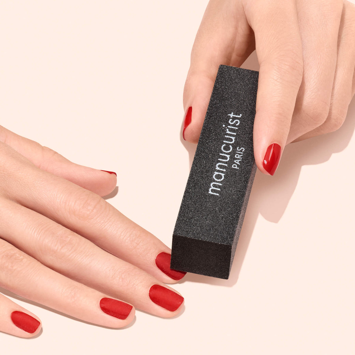 A hand holding a black, rectangular Manucurist-us Flash Removal Block used for manicure removal.
