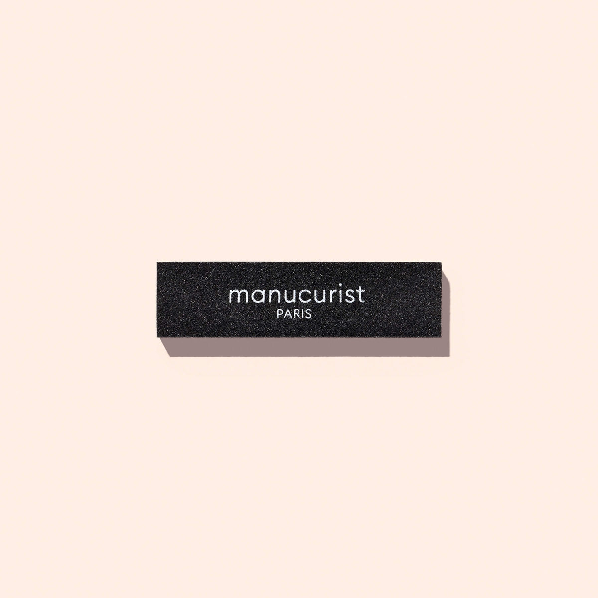 Bloc de dépose rapide Manucurist-us noir et rectangulaire, utilisé pour retirer le Top Coat, avec le nom de la marque imprimé en blanc sur le côté.