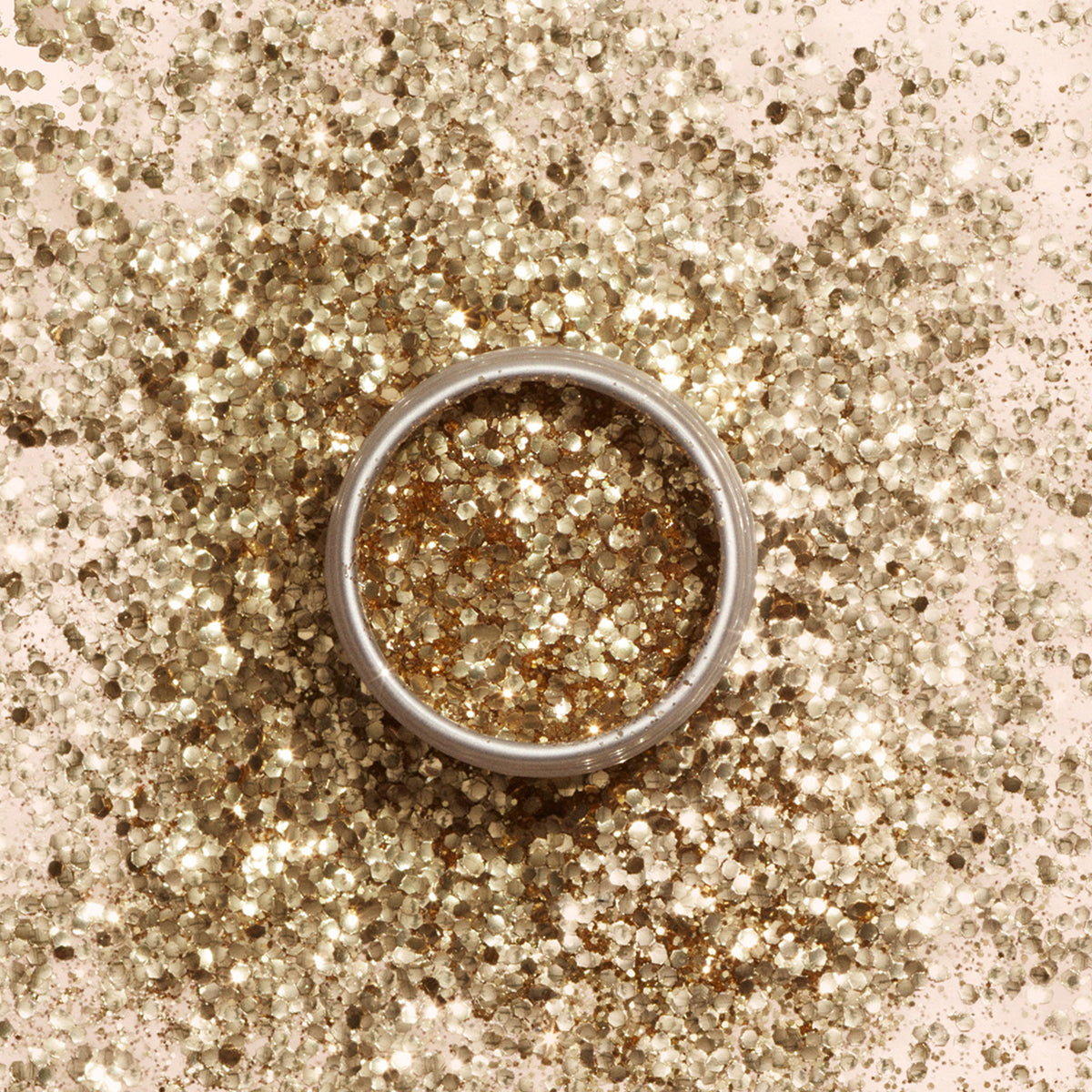 Une bague argentée repose sur une surface parsemée de paillettes biodégradables Manucurist, tandis que davantage de paillettes Manucurist à base de cellulose végétale remplissent l’intérieur de la bague.