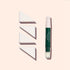A green and pink capped makeup brush stands upright next to three Manucurist Nail Art Sponges (set of 4) arranged in a row on a light beige background.