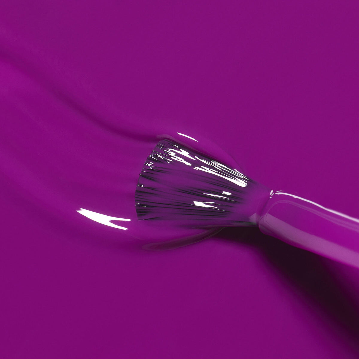 Gros plan sur le pinceau Manucurist Fizz appliquant un vernis violet brillant aux sous-tons magenta, avec des passages lisses visibles sur le fini encore frais.