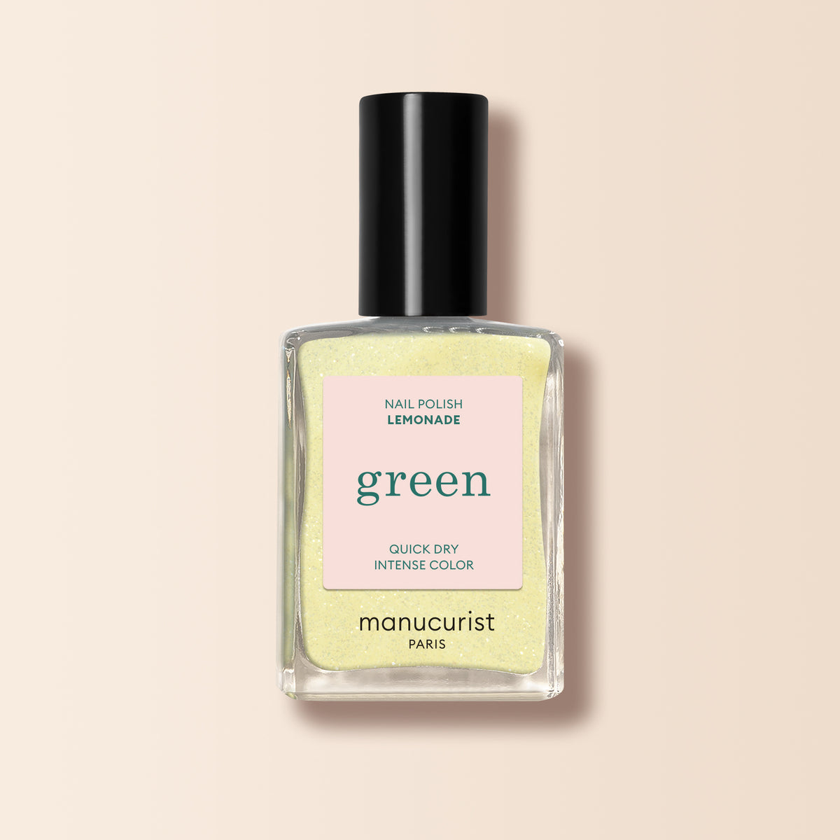 Un flacon de vernis à ongles Manucurist dans la teinte Lemonade, avec une couleur jaune pâle, un capuchon noir et une étiquette carrée portant les mentions « green » et « quick dry intense color ».
