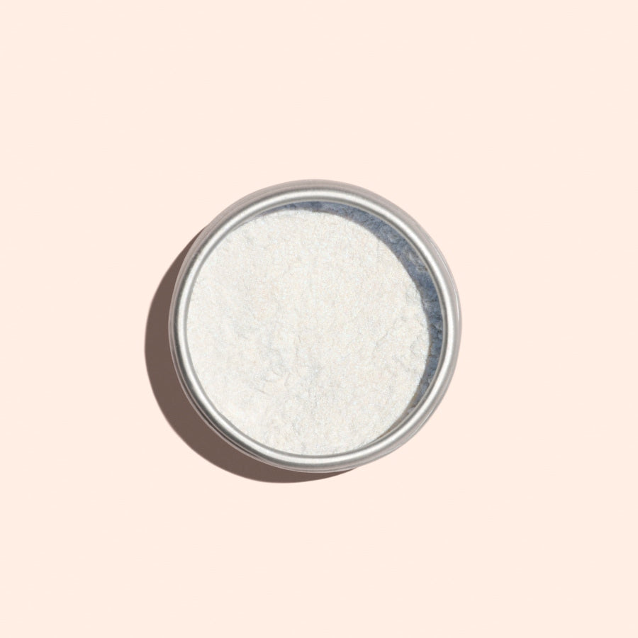 Une boîte ronde en métal de Blue Glazed Powder Manucurist, une fine poudre blanche pour manucure, vue de dessus sur un fond beige clair.