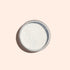 Une boîte ronde en métal de Blue Glazed Powder Manucurist, une fine poudre blanche pour manucure, vue de dessus sur un fond beige clair.