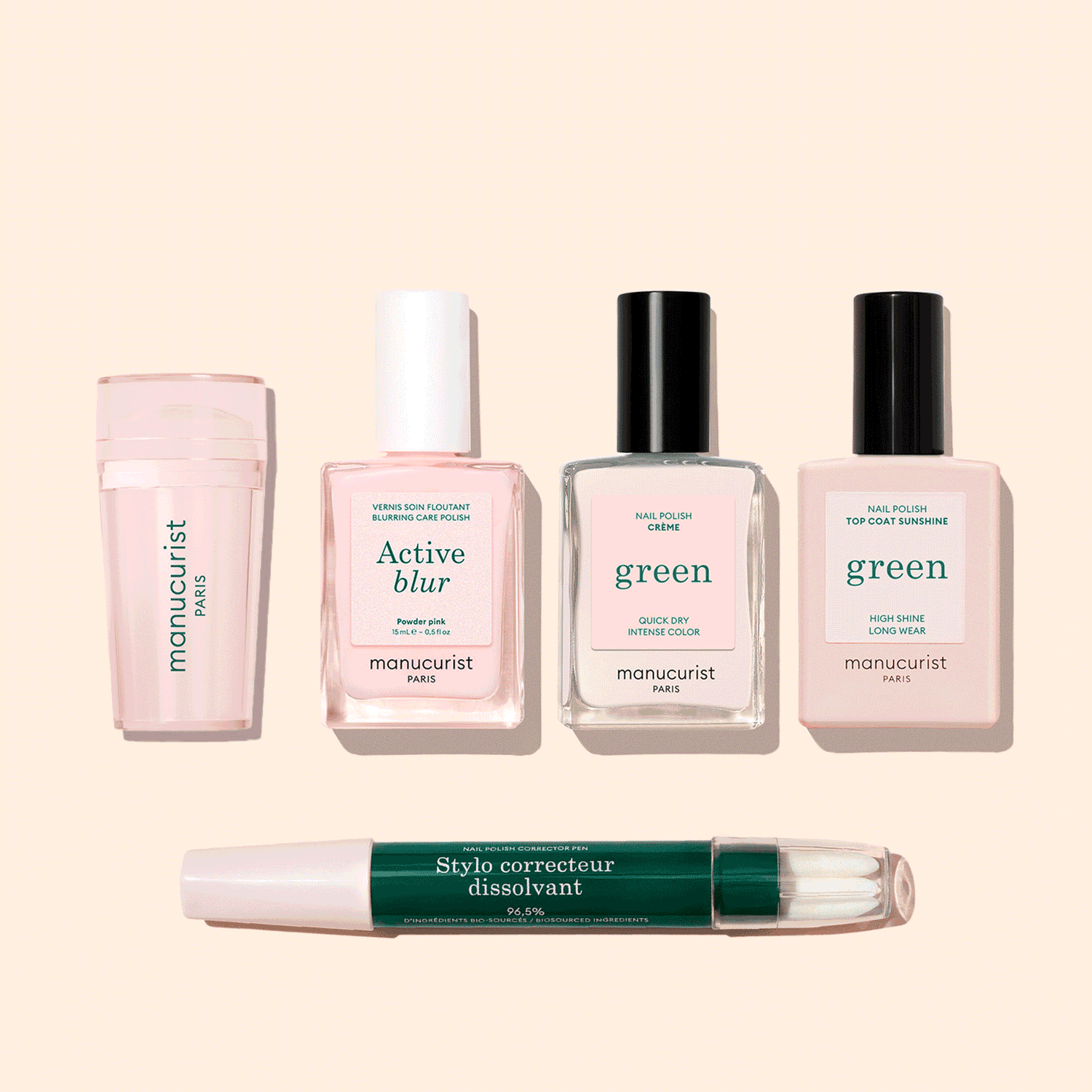 Five manicure products from Manucurist’s French Active™ Kit are shown on a beige background: a pink cylindrical container, a square bottle labeled Active blur, two green-labeled nail polish bottles, and a dual-ended Stylo correcteur pen.