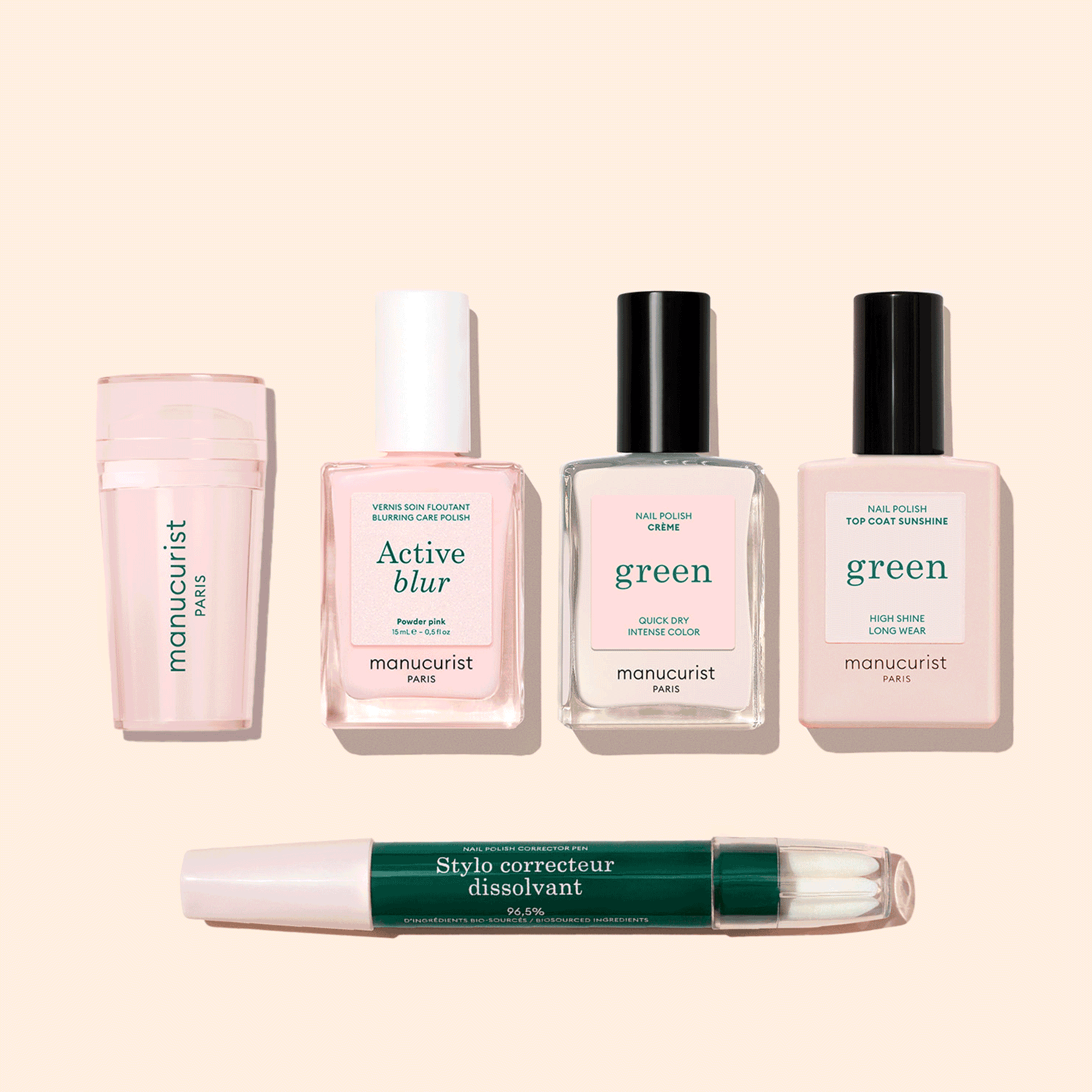 Five manicure products from Manucurist’s French Active™ Kit are shown on a beige background: a pink cylindrical container, a square bottle labeled Active blur, two green-labeled nail polish bottles, and a dual-ended Stylo correcteur pen.