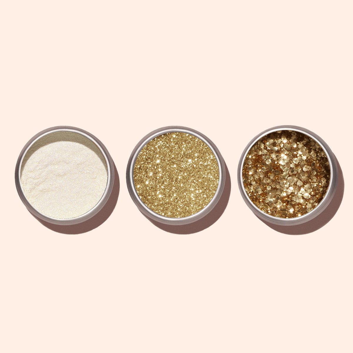 Three round Manucurist containers, each holding a different type of glitter—including Golden Chrome Powder for a chrome finish—are arranged in a row on a light beige background, showcasing varying glitter textures and sizes.