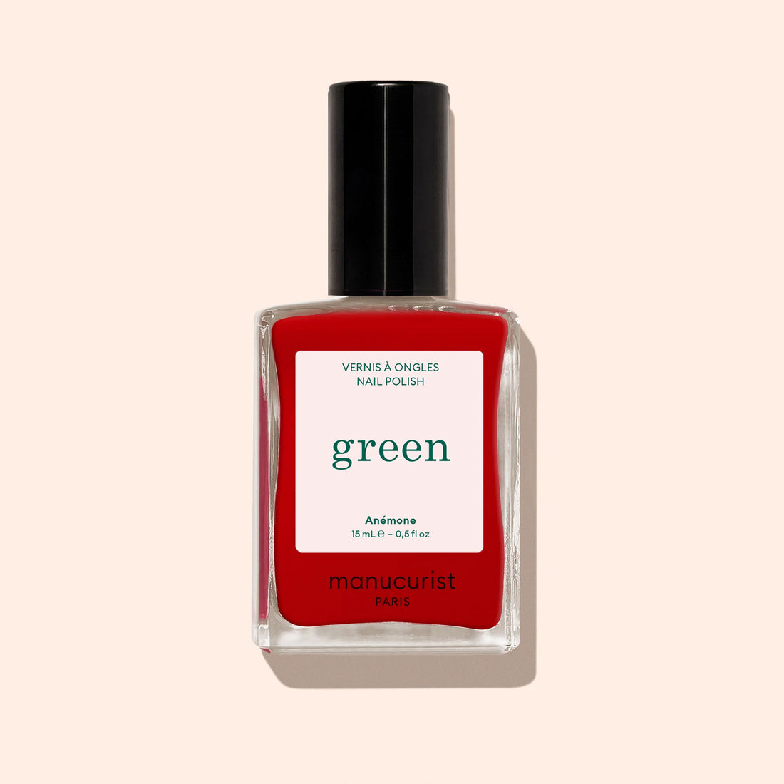 Un flacon de vernis à ongles rouge vif aux sous-tons bleus, avec un bouchon noir et une étiquette blanche portant la mention Manucurist Anémone.