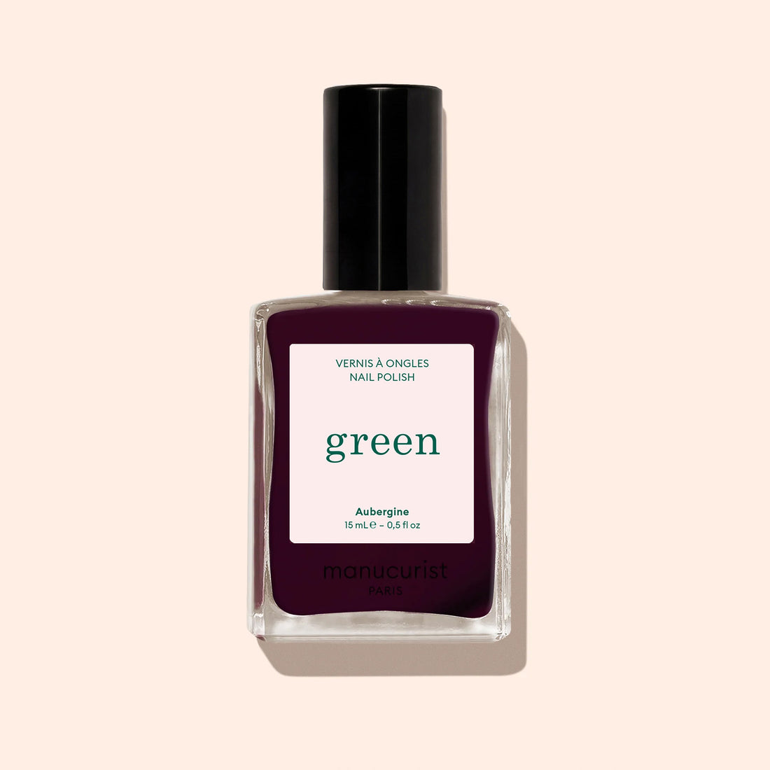 Un flacon en verre de vernis à ongles Manucurist teinte Aubergine, d’un violet profond, avec une étiquette blanche.