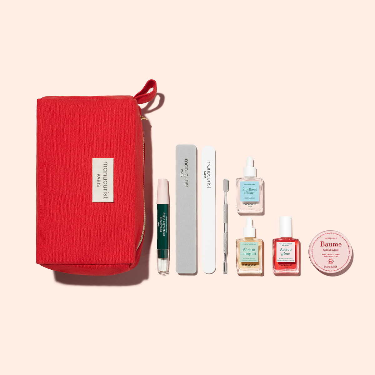 Une trousse rouge Manucurist marquée "Paris" présente le Healthy Glow Duo, comprenant un stylo sérum à embout vert, deux limes à ongles, un repousse-cuticules, trois flacons de soin ou vernis à ongles, ainsi qu&