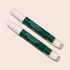 Two green and white Manucurist-test [Test jauge] Nail Polish Corrector Pens with clear caps, labeled "Stylo correcteur dissolvant," are positioned diagonally on a light beige background—ideal for precise gel polish touch-ups.