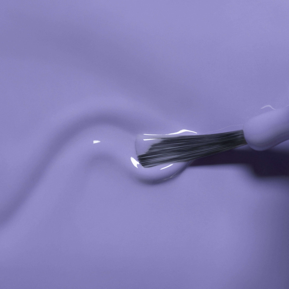 A close-up of a brush applying Manucurist’s Hector the Stegosaurus kids nail polish, creating shiny lavender curves on a smooth surface with safe, natural ingredients.