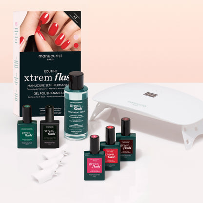 The Manucurist Starter Kit includes four Green Flash gel polishes, a vitaminized base coat, remover, and white UV lamp in a box—everything you need for an ultra-glossy manicure. Displayed on a pink and white surface with manicured hands.