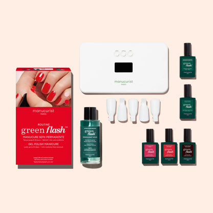 The Manucurist Starter Kit includes a red box, ultra-glossy green and red gel polishes, white LED lamp, vitamin-enriched base coat, nail polish remover, and four white remover clips—all arranged on a beige background.